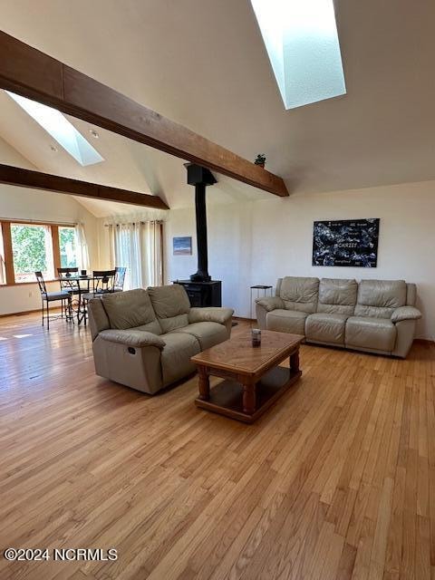 living room featuring light wood-type flooring, lofted ceiling with skylight, and a wood stove