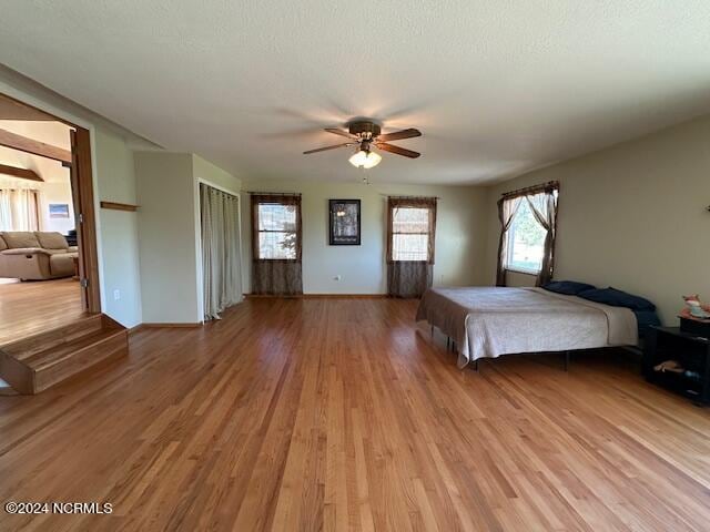 unfurnished bedroom with light wood-type flooring, a textured ceiling, and ceiling fan