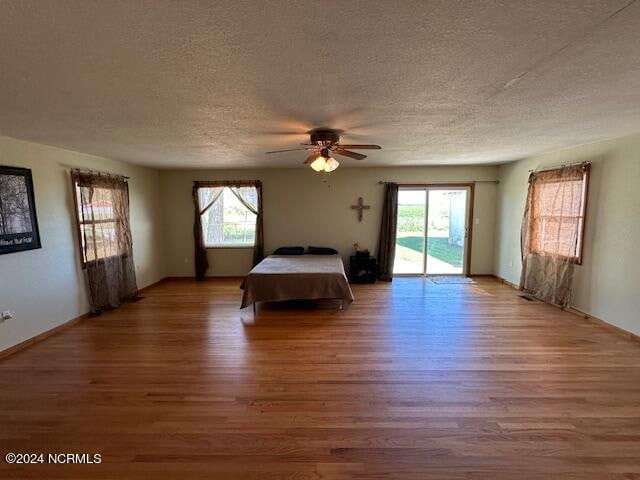 unfurnished bedroom featuring multiple windows, hardwood / wood-style floors, and a textured ceiling