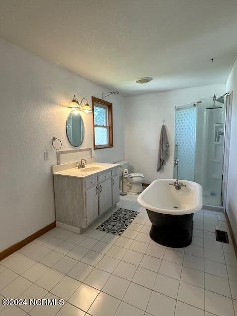 bathroom with tile patterned floors, a shower with door, vanity, and toilet