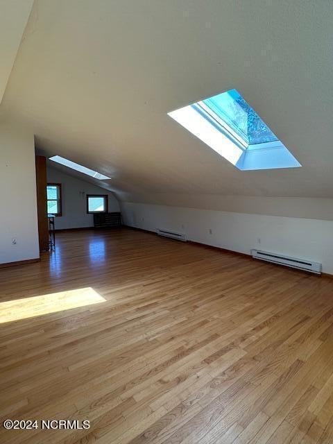 bonus room featuring a baseboard heating unit, lofted ceiling, and light hardwood / wood-style floors