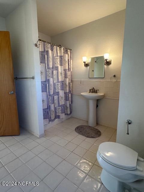 bathroom with a shower with shower curtain, tile walls, tile patterned floors, and toilet