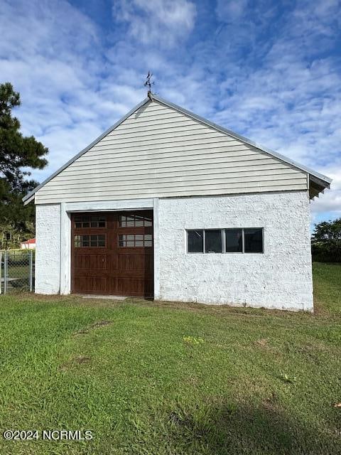 view of property exterior with a garage, a lawn, and an outbuilding