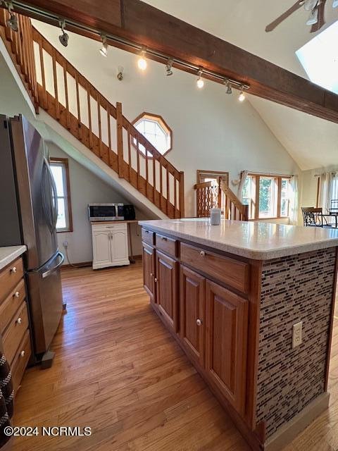 kitchen featuring light hardwood / wood-style floors, rail lighting, stainless steel refrigerator, and a center island