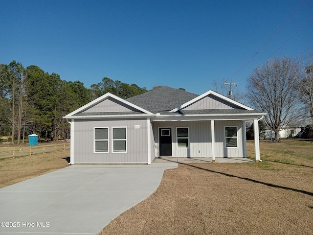 view of front of house featuring a front lawn, roof with shingles, and a porch