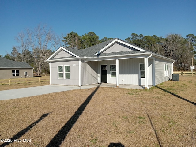 view of front of property with a shingled roof, cooling unit, and a front lawn