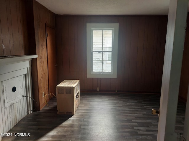 unfurnished living room featuring wooden walls and dark hardwood / wood-style flooring