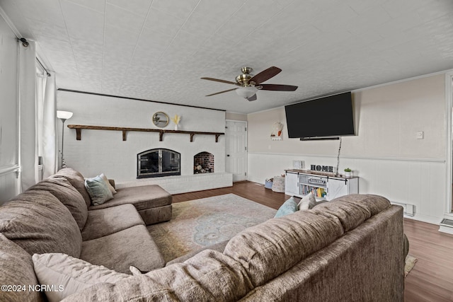 living room featuring a brick fireplace, dark hardwood / wood-style floors, a baseboard heating unit, and ceiling fan