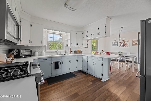 kitchen featuring pendant lighting, stainless steel appliances, kitchen peninsula, and dark wood-type flooring