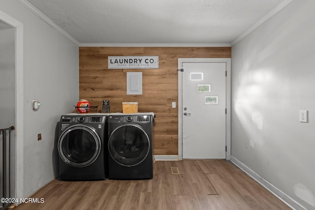 laundry area with wood walls, hardwood / wood-style flooring, washer and clothes dryer, and crown molding