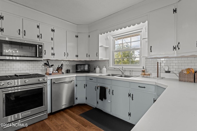 kitchen with dark hardwood / wood-style flooring, stainless steel appliances, white cabinetry, and sink