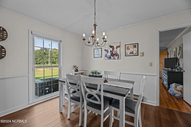 dining space with ornamental molding, a notable chandelier, hardwood / wood-style flooring, and a textured ceiling