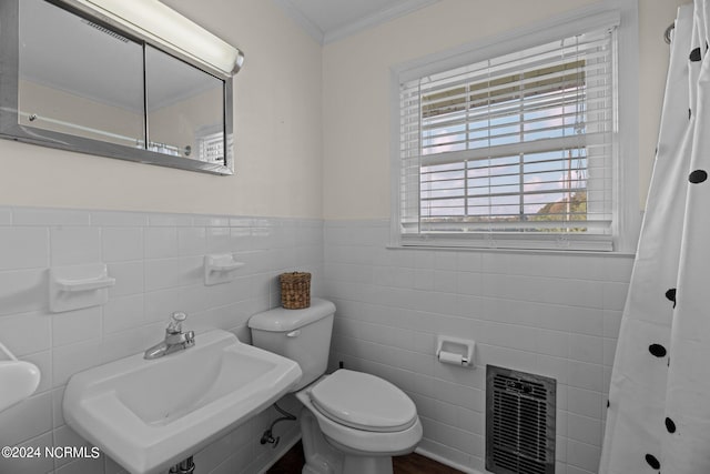 bathroom with tile walls, crown molding, toilet, and sink