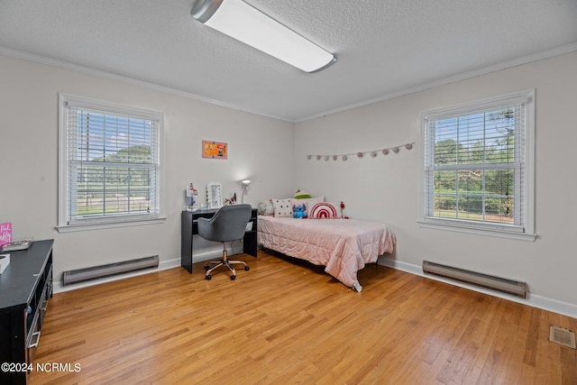 bedroom with baseboard heating, crown molding, and light hardwood / wood-style floors