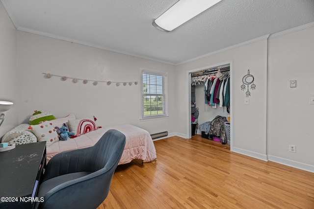 bedroom with ornamental molding, wood-type flooring, a textured ceiling, a closet, and a baseboard radiator