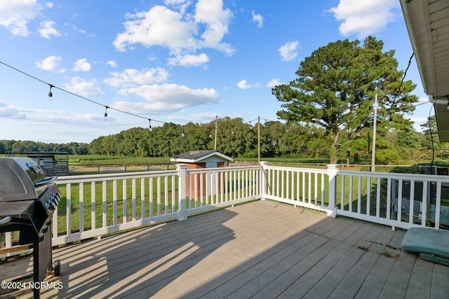 wooden deck with a lawn, an outdoor structure, and a grill