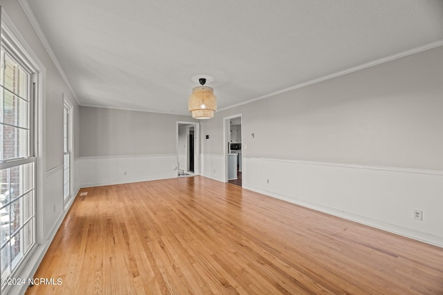 unfurnished room with a textured ceiling, crown molding, and light hardwood / wood-style flooring