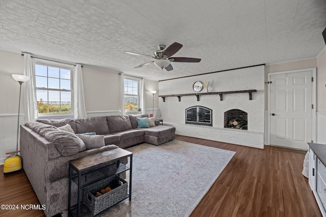 living room with ceiling fan, a fireplace, crown molding, and dark hardwood / wood-style flooring