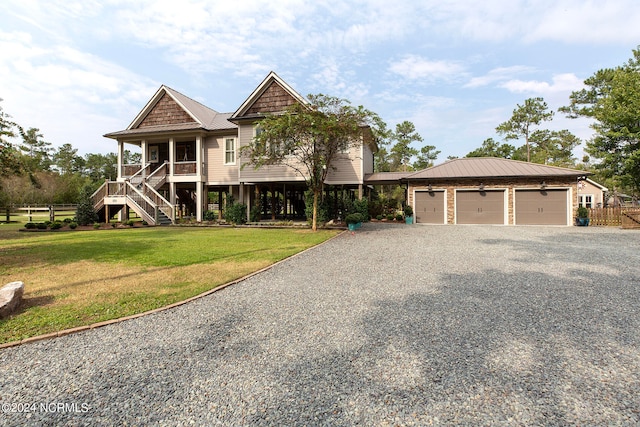 view of front of home featuring covered porch, a garage, and a front lawn