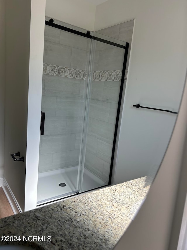 bathroom with wood-type flooring and a shower with door