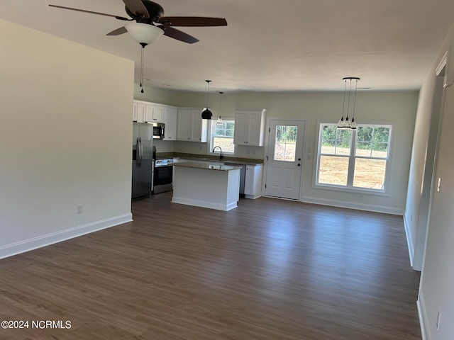 kitchen featuring appliances with stainless steel finishes, white cabinetry, a healthy amount of sunlight, and a center island