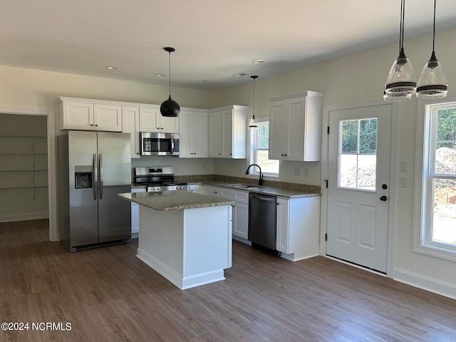 kitchen with sink, white cabinetry, appliances with stainless steel finishes, dark hardwood / wood-style floors, and a center island