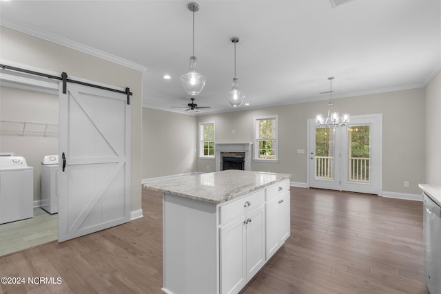 kitchen featuring washing machine and clothes dryer, light wood-style flooring, baseboards, a stone fireplace, and ornamental molding
