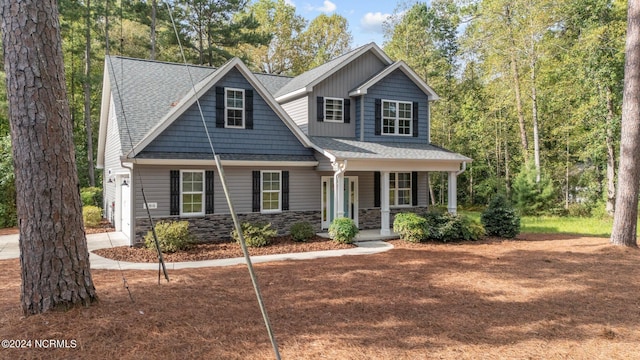 craftsman inspired home with roof with shingles, stone siding, concrete driveway, and covered porch