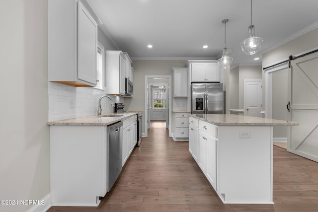kitchen with stainless steel appliances, a sink, a barn door, and crown molding