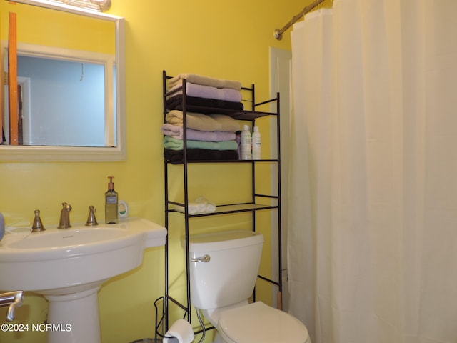 bathroom featuring sink, toilet, and curtained shower