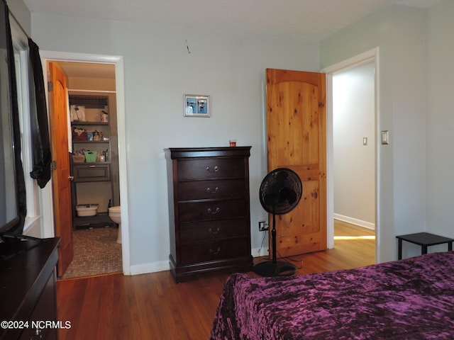 bedroom with ensuite bath and dark wood-type flooring