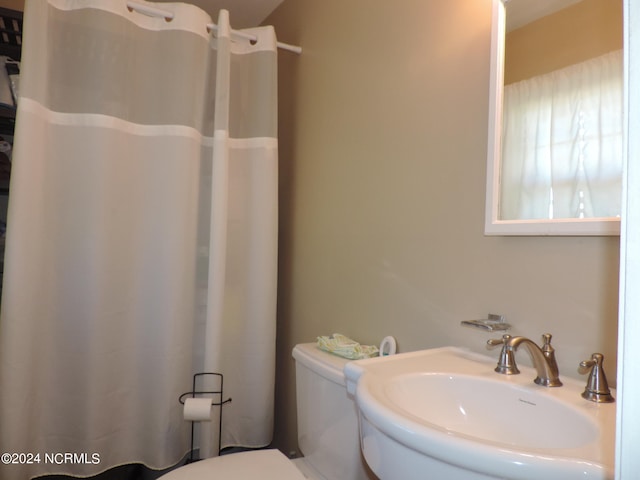 bathroom featuring toilet, a shower with shower curtain, and sink