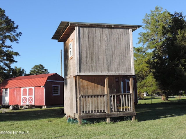 rear view of house with a storage shed and a yard