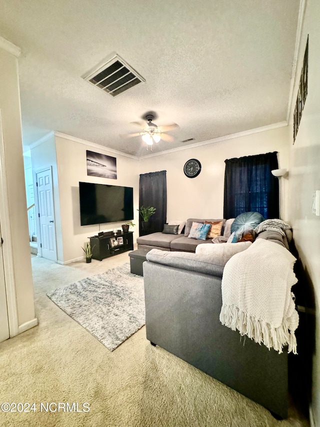 living room with a textured ceiling, ornamental molding, ceiling fan, and carpet floors