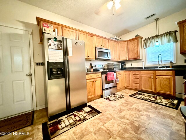 kitchen with a textured ceiling, sink, stainless steel appliances, decorative light fixtures, and ceiling fan