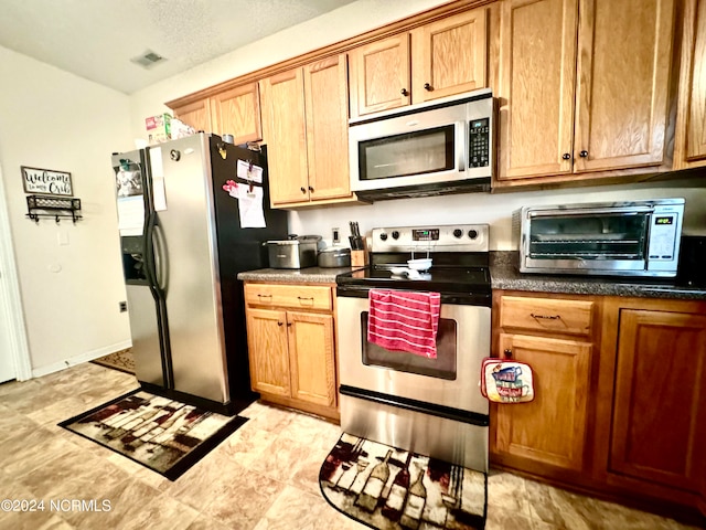 kitchen with a textured ceiling and appliances with stainless steel finishes