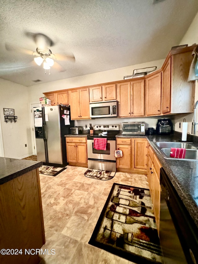 kitchen with stainless steel appliances, a textured ceiling, ceiling fan, and sink