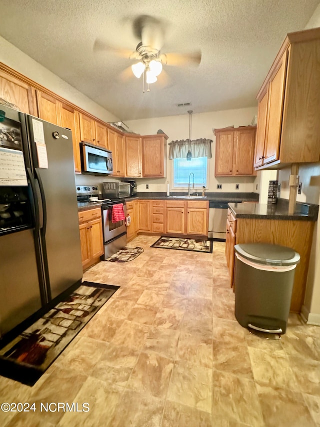 kitchen featuring ceiling fan, sink, a textured ceiling, decorative light fixtures, and appliances with stainless steel finishes