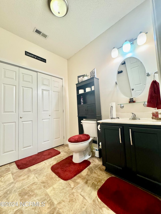 bathroom with a textured ceiling, vanity, and toilet