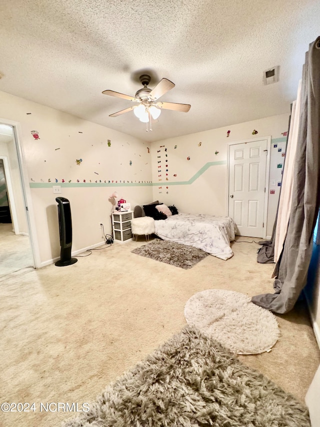 bedroom featuring ceiling fan, carpet floors, and a textured ceiling