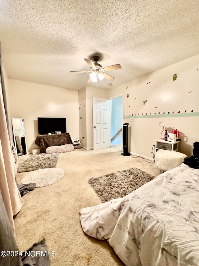 carpeted bedroom with ceiling fan and a textured ceiling