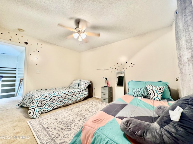 bedroom with a textured ceiling, ceiling fan, and light colored carpet