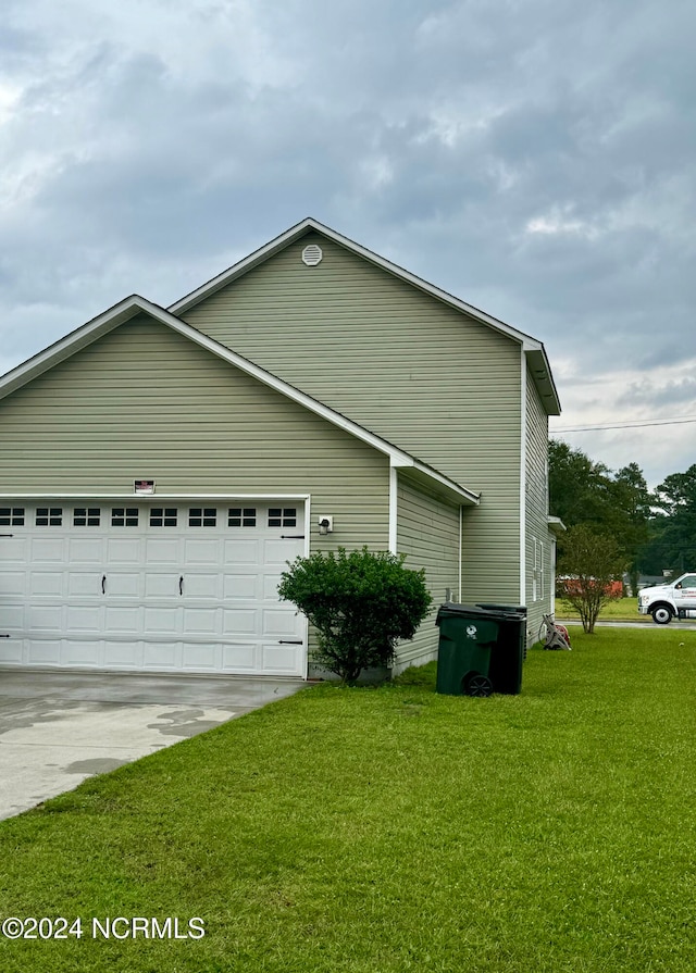 view of side of home featuring a garage and a lawn