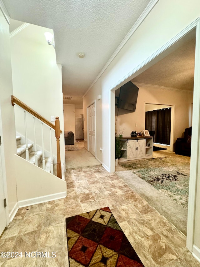 hall with a textured ceiling and crown molding