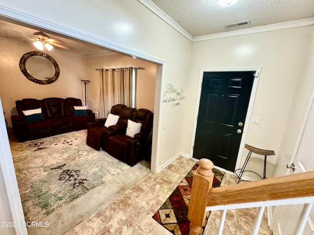 entrance foyer with ornamental molding, a textured ceiling, and ceiling fan