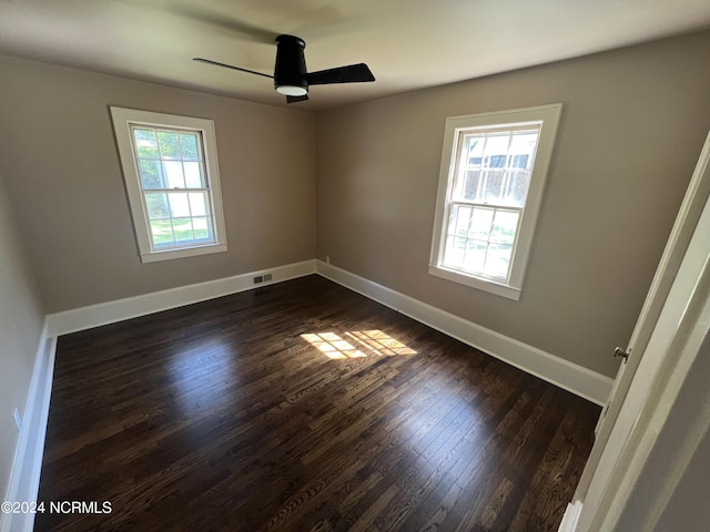 spare room with a ceiling fan, baseboards, dark wood-style flooring, and visible vents