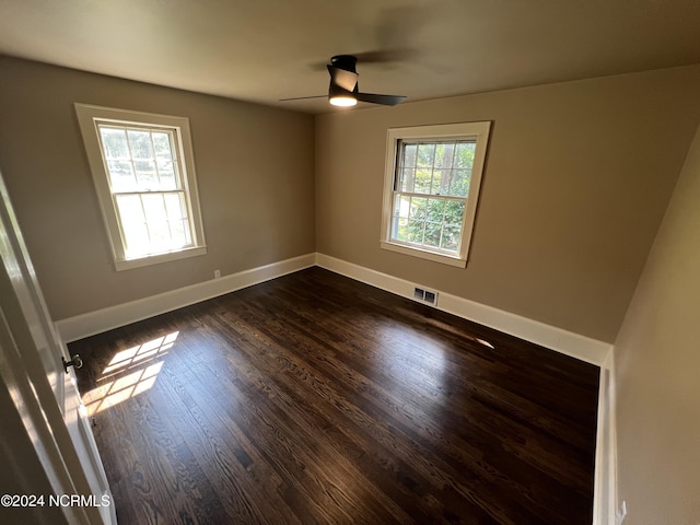 unfurnished room with ceiling fan, baseboards, visible vents, and dark wood-style floors