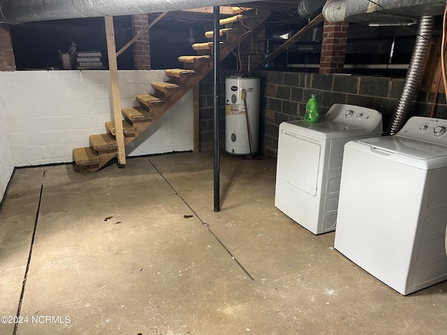 unfinished basement with water heater, concrete block wall, and washing machine and dryer