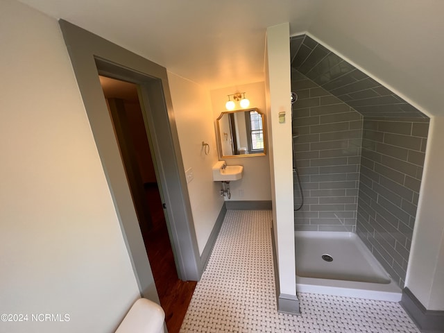 full bath featuring a sink, toilet, a stall shower, baseboards, and lofted ceiling