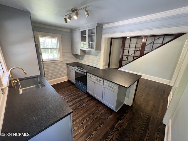 kitchen featuring a sink, dark wood finished floors, stainless steel electric range, dark countertops, and baseboards